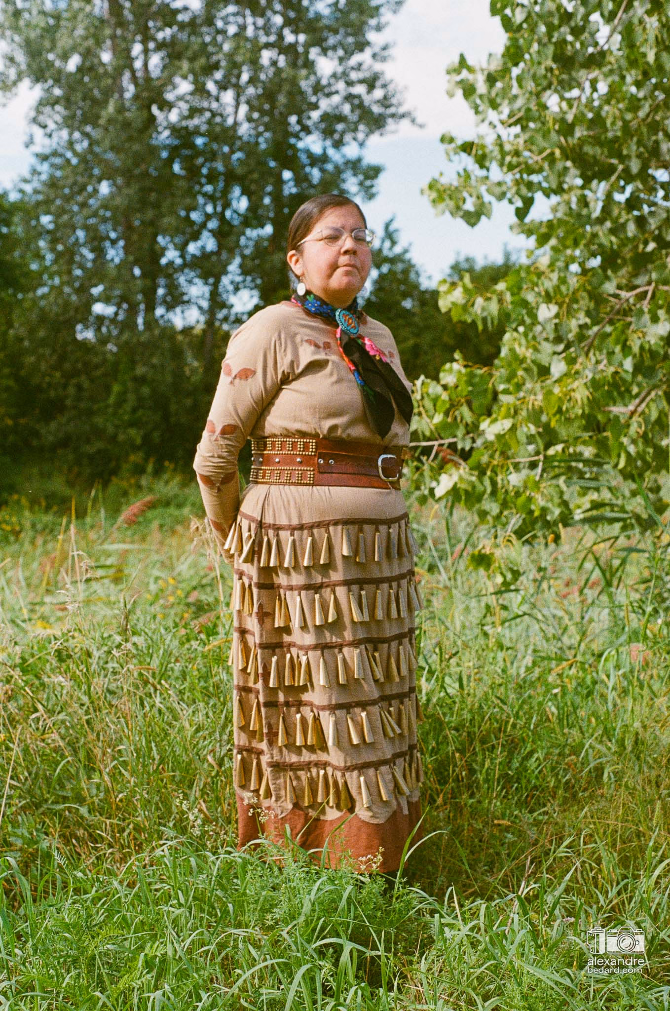Portrait en photographie argentique d'une femme participante arborant une regalia traditionnelle richement ornée de perles et de rubans