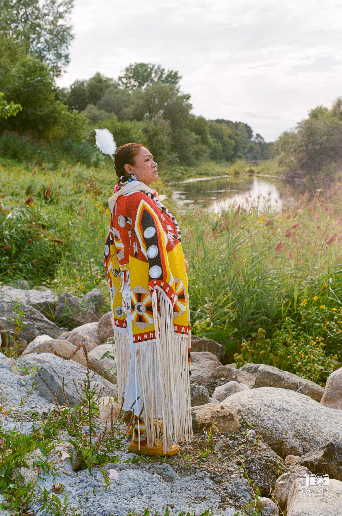 Portrait en photographie argentique d'une femme participante arborant une regalia traditionnelle richement ornée de perles et de rubans