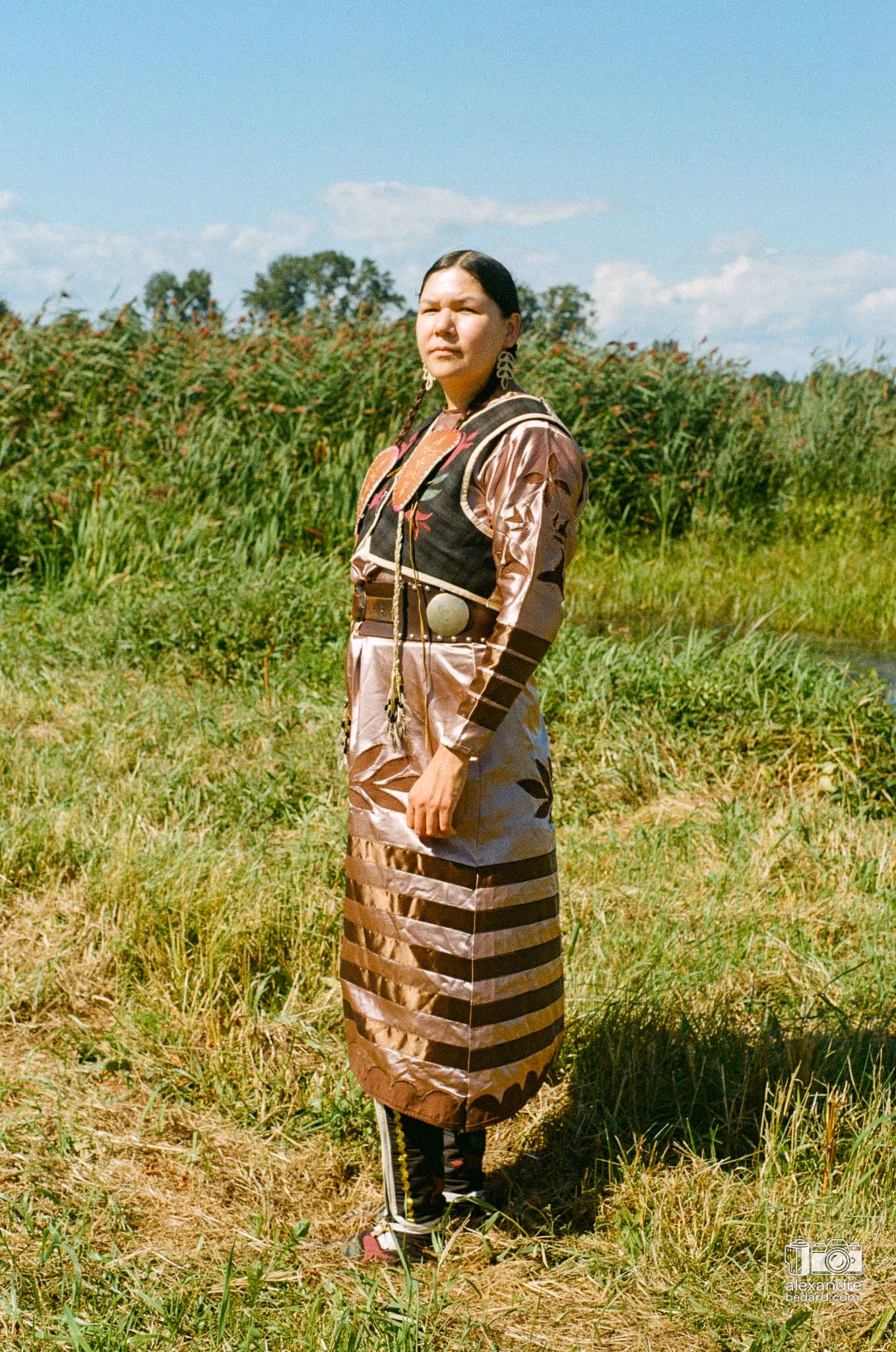 Portrait en photographie argentique d'une femme participante arborant une regalia traditionnelle richement ornée de perles et de rubans