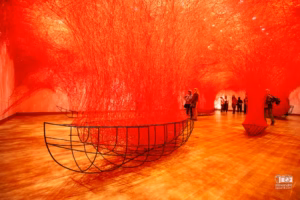 Installation d'art immersif de Chiharu Shiota au MBAM montrant un réseau dense de fils rouges tissés du sol au plafond.